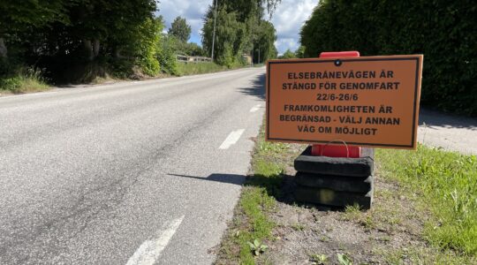 Bild som visar en orange skylt med information om en kommande vägavstängning på bilväg.